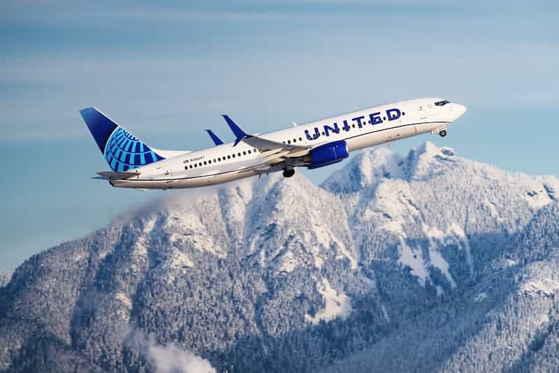 United Airlines plane flying over snow-covered mountains